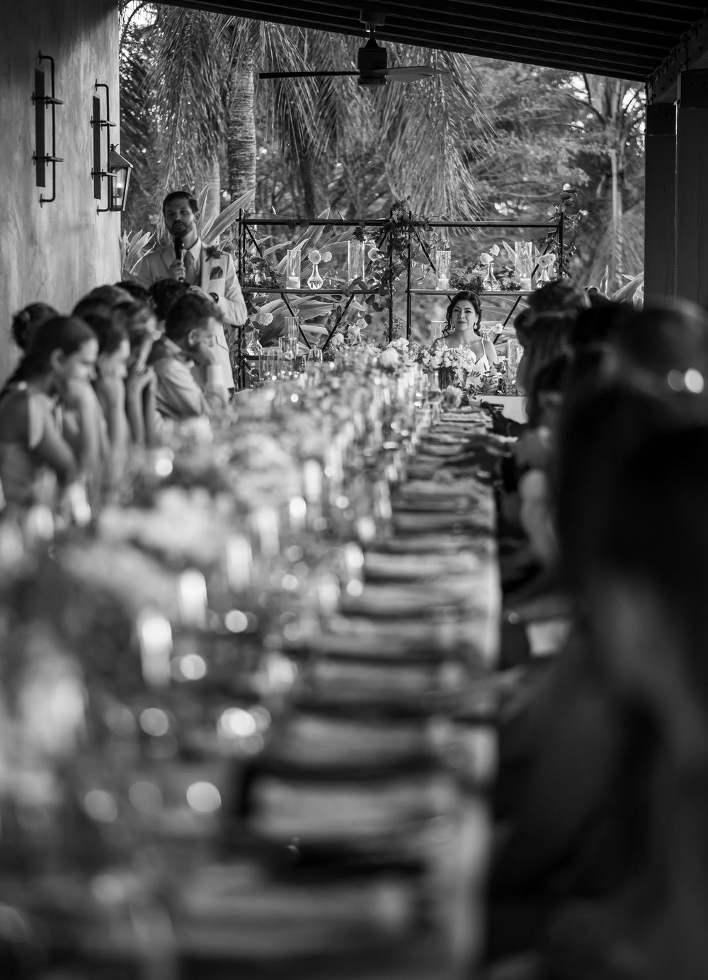 Long elegant dining table set up for a wedding reception in a covered outdoor space.