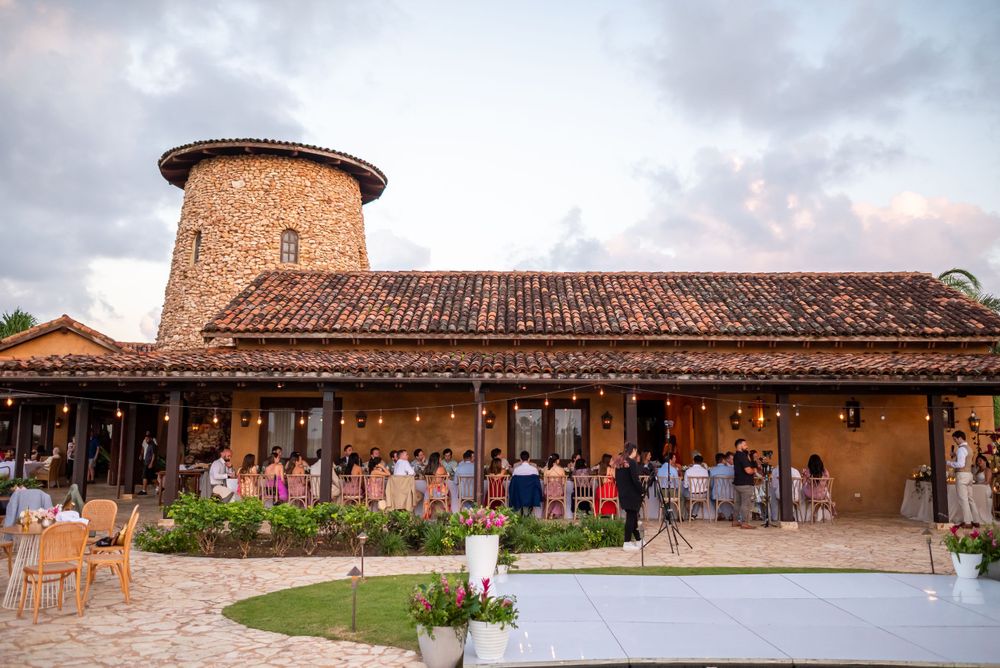 Rustic wedding venue with terra cotta walls and tower featuring outdoor seating and decorative lighting.