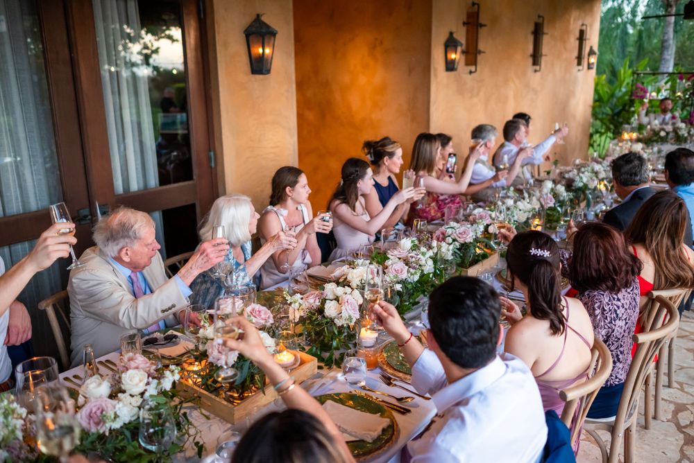 Wedding reception dinner with guests seated at a long decorated table on an outdoor terrace.