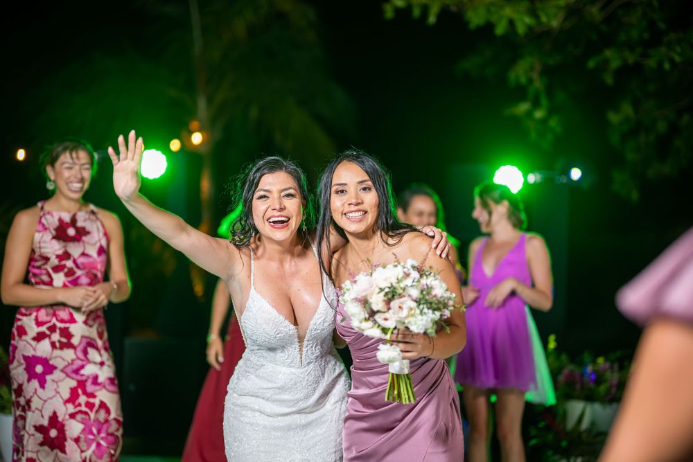 Wedding party celebrating on a lit dance floor with green accent lighting.