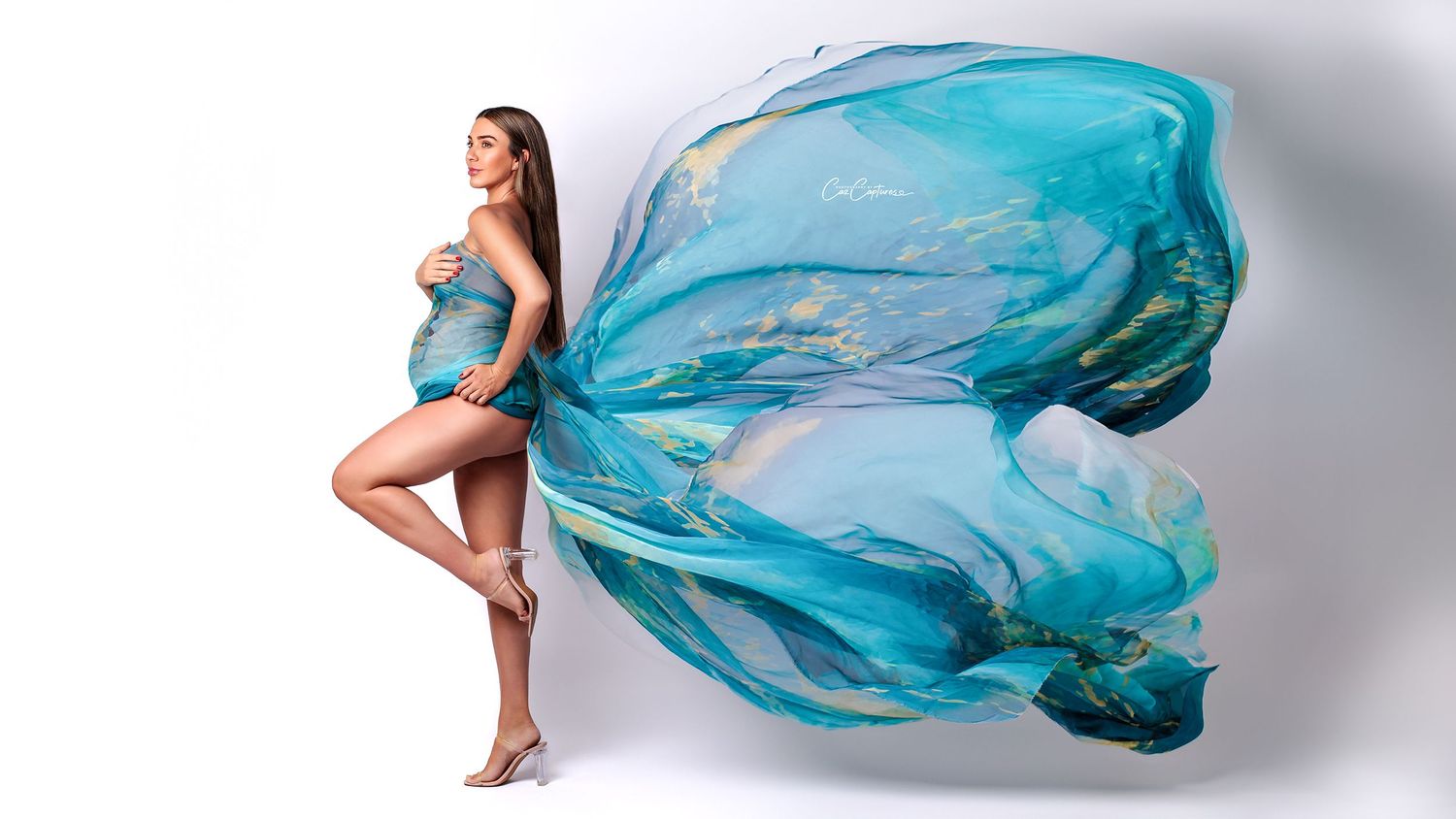 Simple elegance: mum-to-be in a turquoise form-fitting chiffon scarf in a light-filled studio.