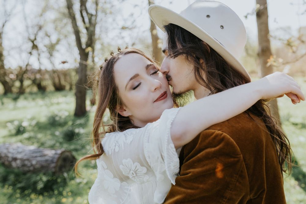 Two people sharing an intimate embrace in a sunny spring garden with natural sunlit bokeh background.