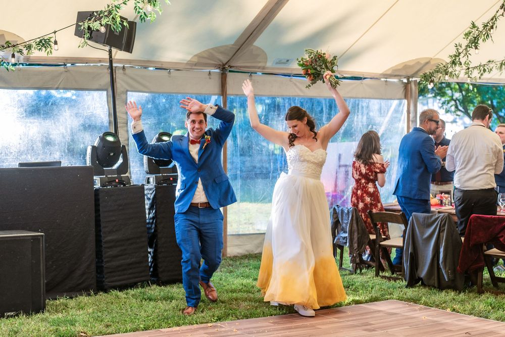 People dancing and celebrating under a white tent at an outdoor event.