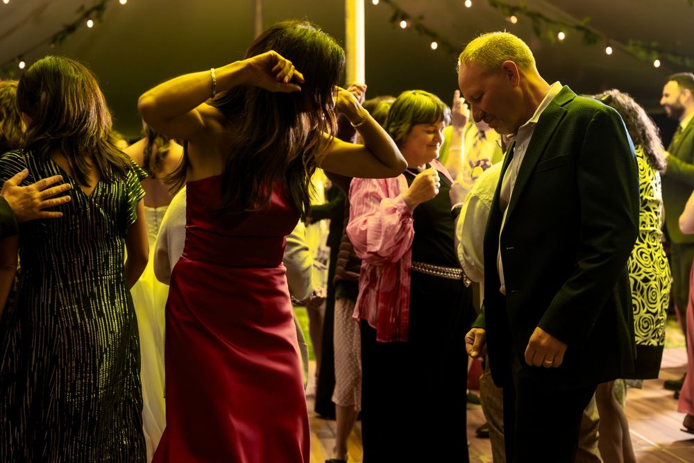 Lively dance floor with guests enjoying a wedding celebration under warm lighting.