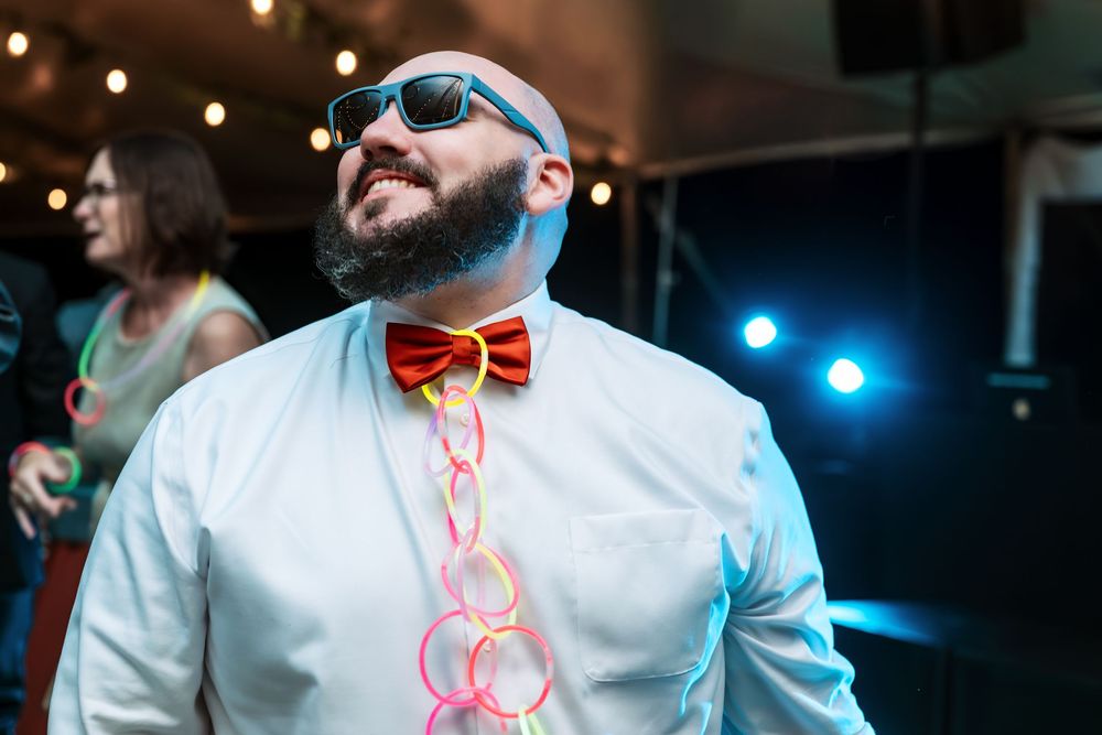 Guests dancing at a wedding reception with colorful lighting and festive atmosphere.