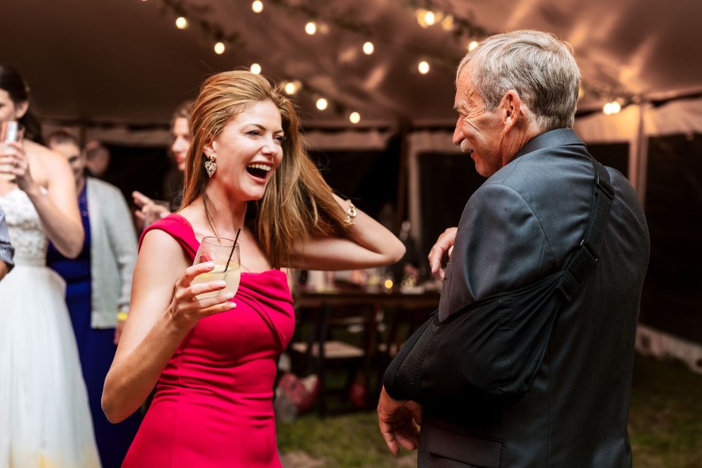 Wedding guests celebrating on a dance floor illuminated by string lights.