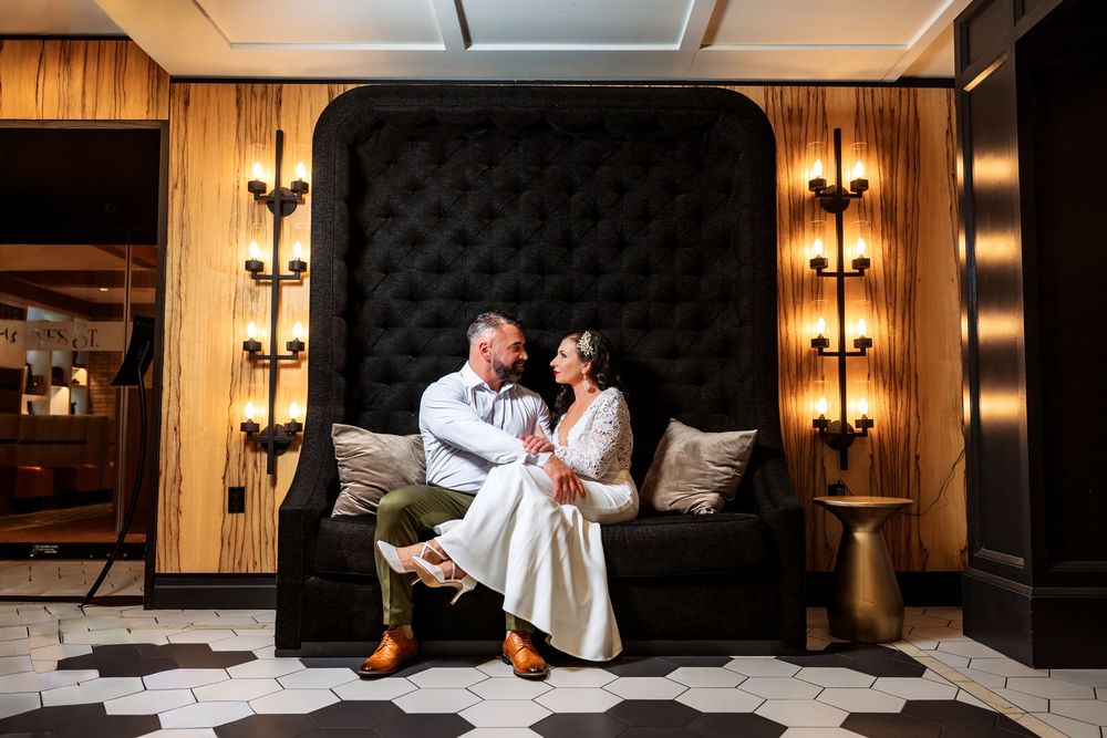 Elegant black tufted headboard and wall sconces create a luxurious bedroom setting.