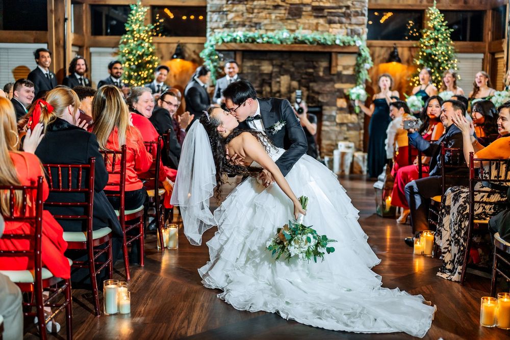 An elegant indoor wedding reception with Christmas trees and string lights decorating a rustic venue.