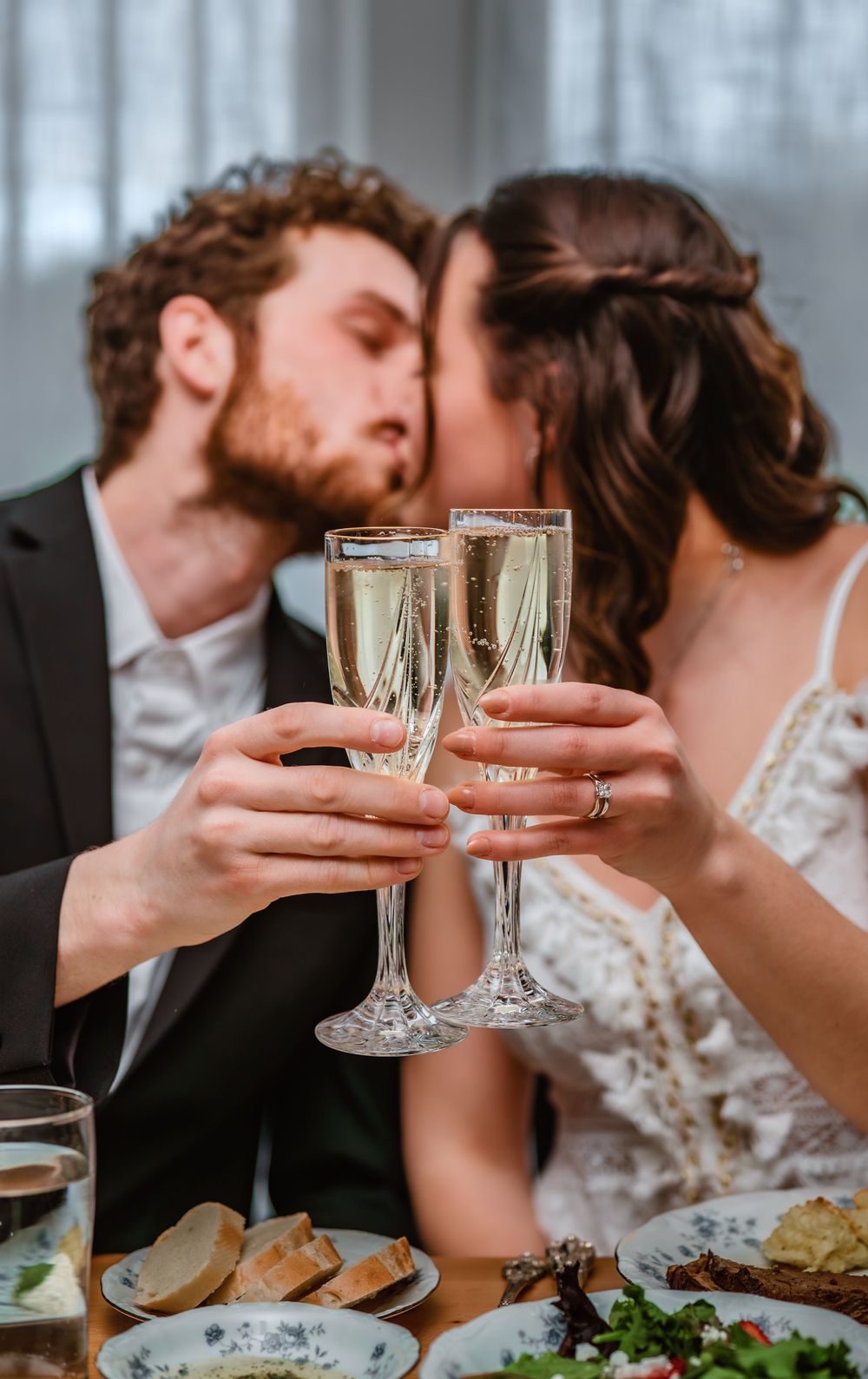 A couple toasting with champagne glasses over a beautifully set dinner table.