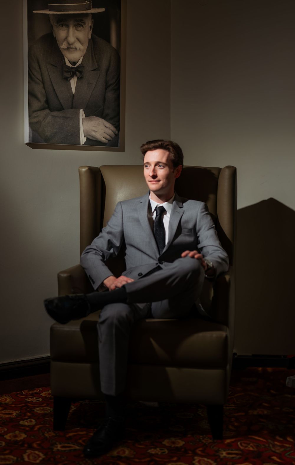 Moody portrait session in dark room with person seated in leather armchair.