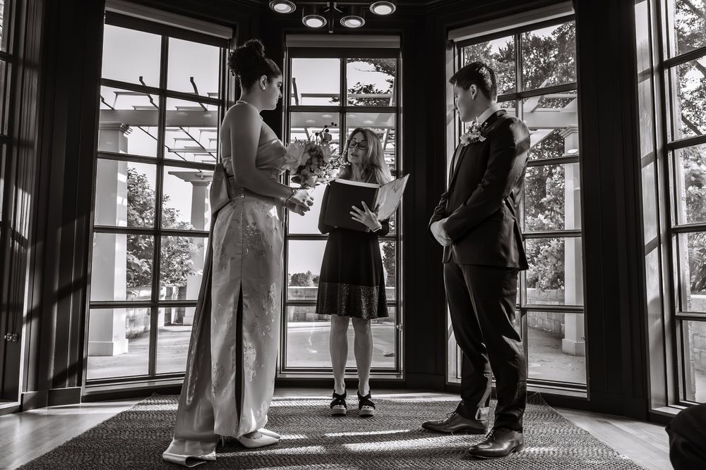 A couple dances in a sunlit room with large windows and dramatic lighting.