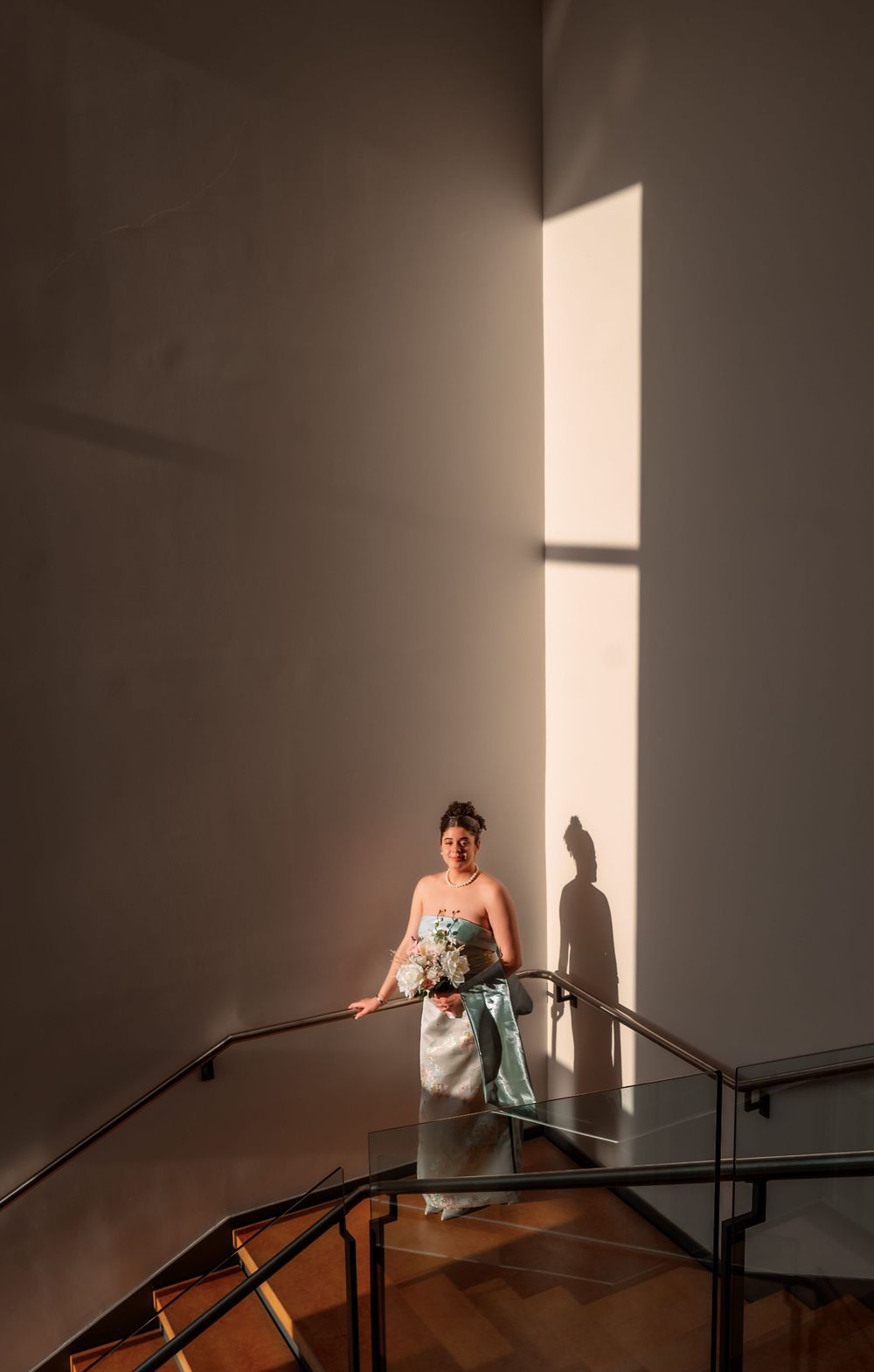 A dramatic scene with sunlight streaming through windows onto a dark wall with handrails.