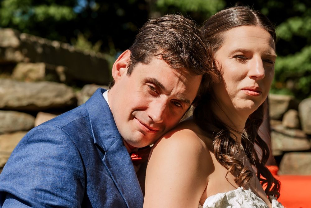 Couple sharing intimate moment near red tractor in outdoor garden setting.