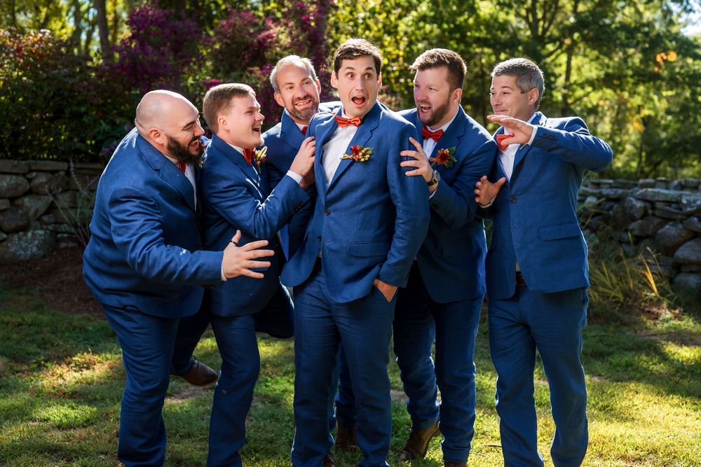 Groomsmen in navy suits sharing laughs during outdoor wedding photo session.