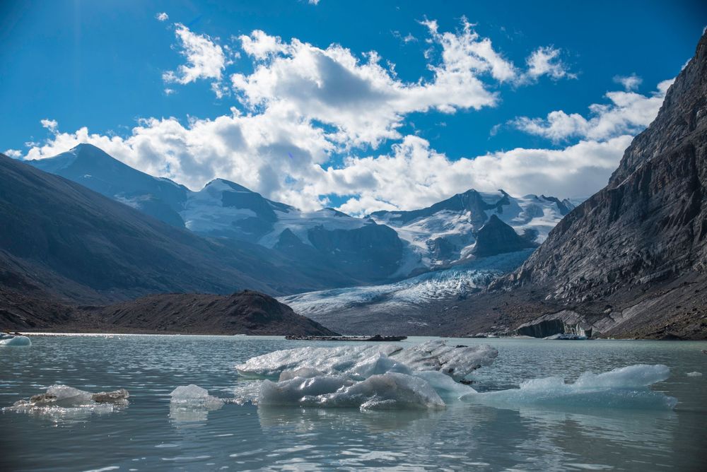 Glacial lake surrounded by rugged mountain peaks with dramatic clouds in the Canadian Rockies.
