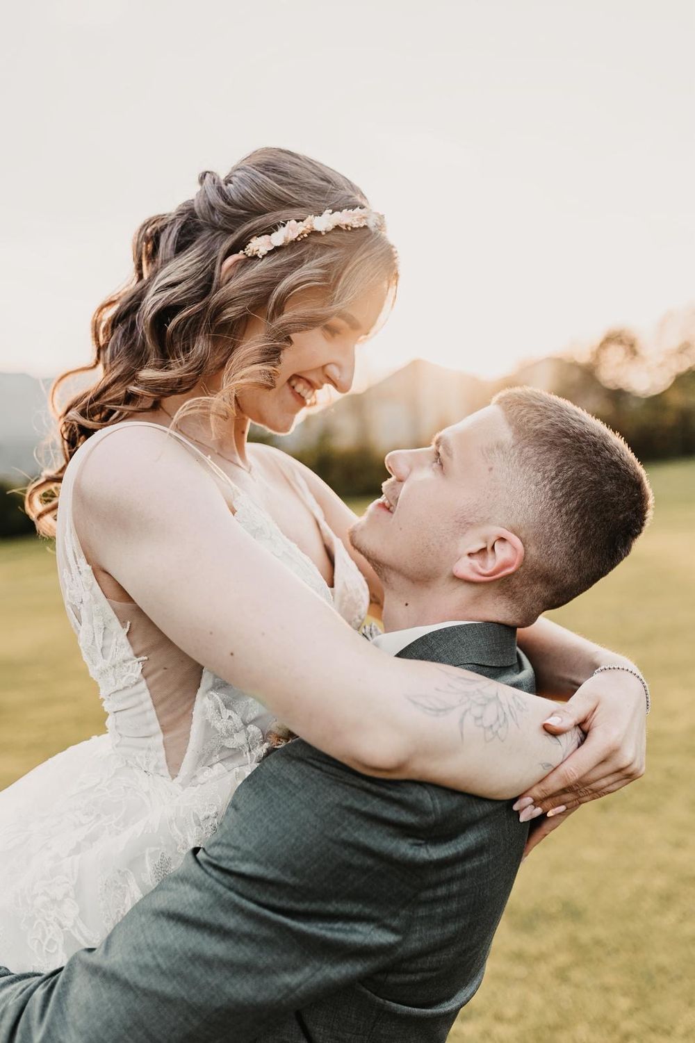 Romantic sunset wedding photos of couple embracing in an open field.