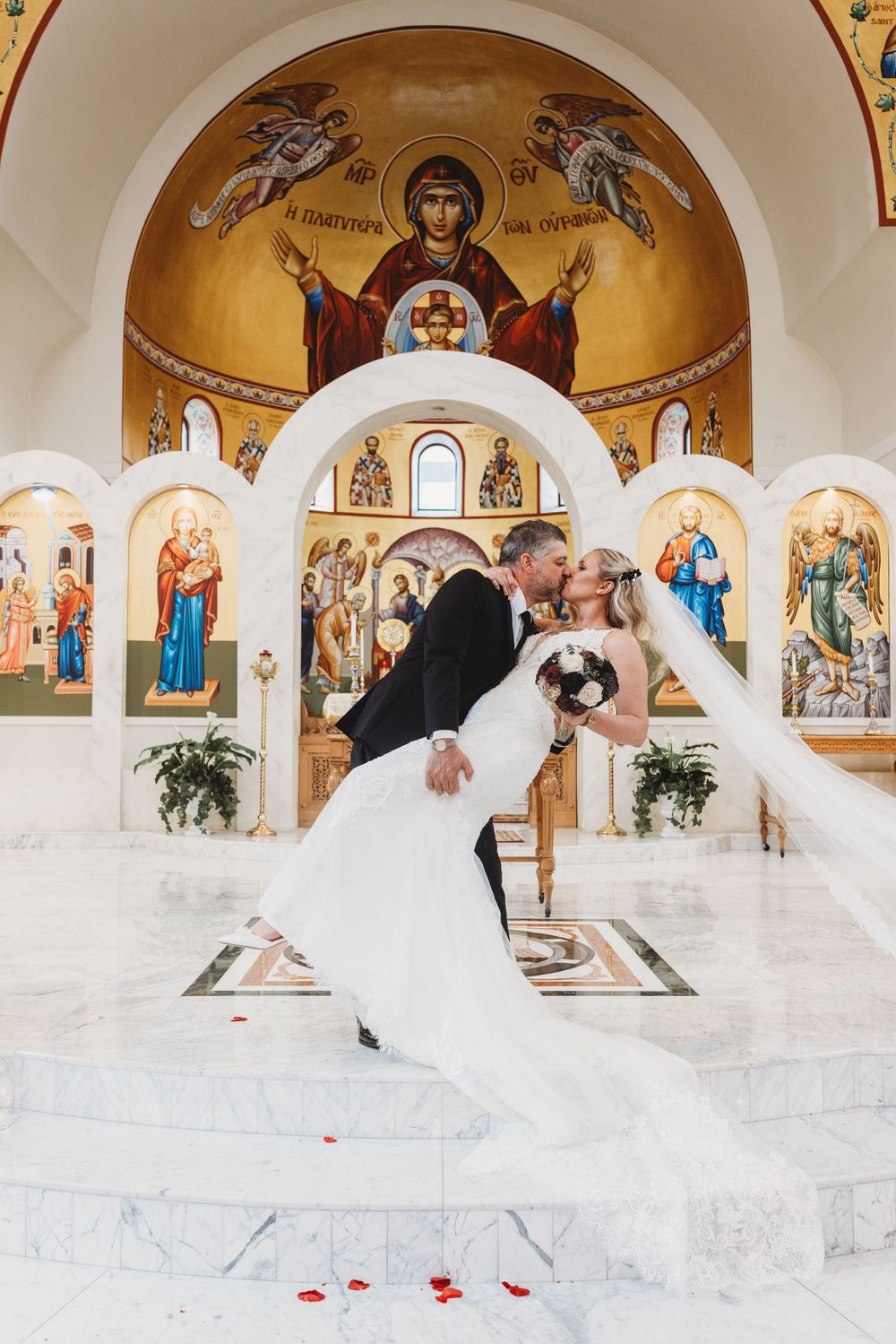 Orthodox church interior with white marble floors and golden religious iconography on arched walls and ceiling.
