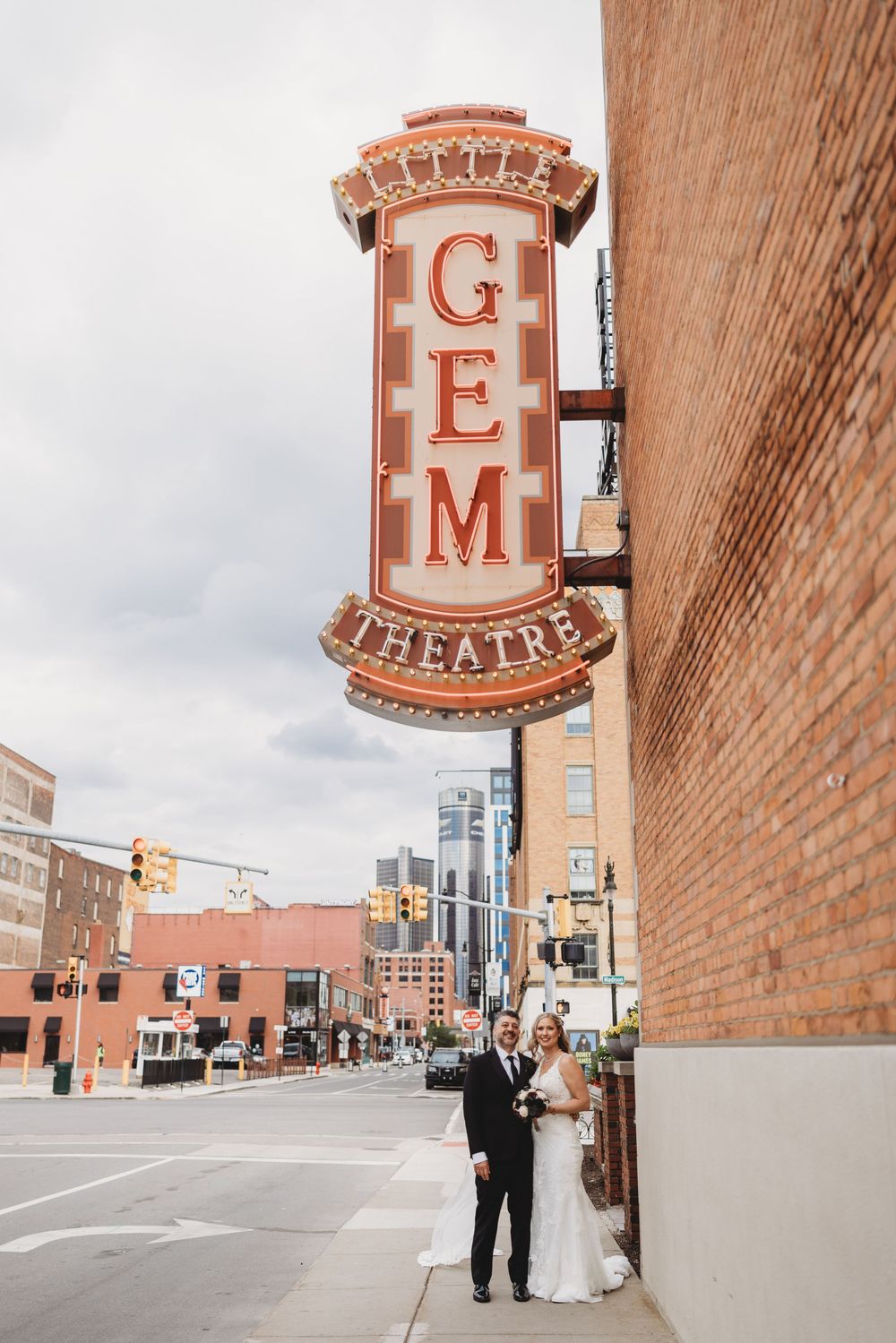 A couple poses outside a historic theater with vintage brick walls and classic signage.