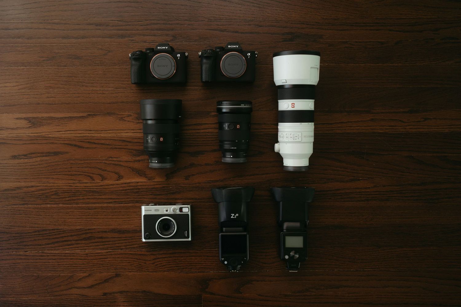A black DSLR camera with lens disassembled into parts shown in sequence on a white surface.