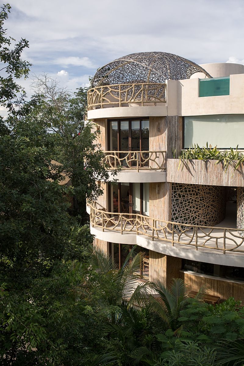 Modern luxury villa with geometric architecture and wood accents nestled among tropical trees in a forest setting.
