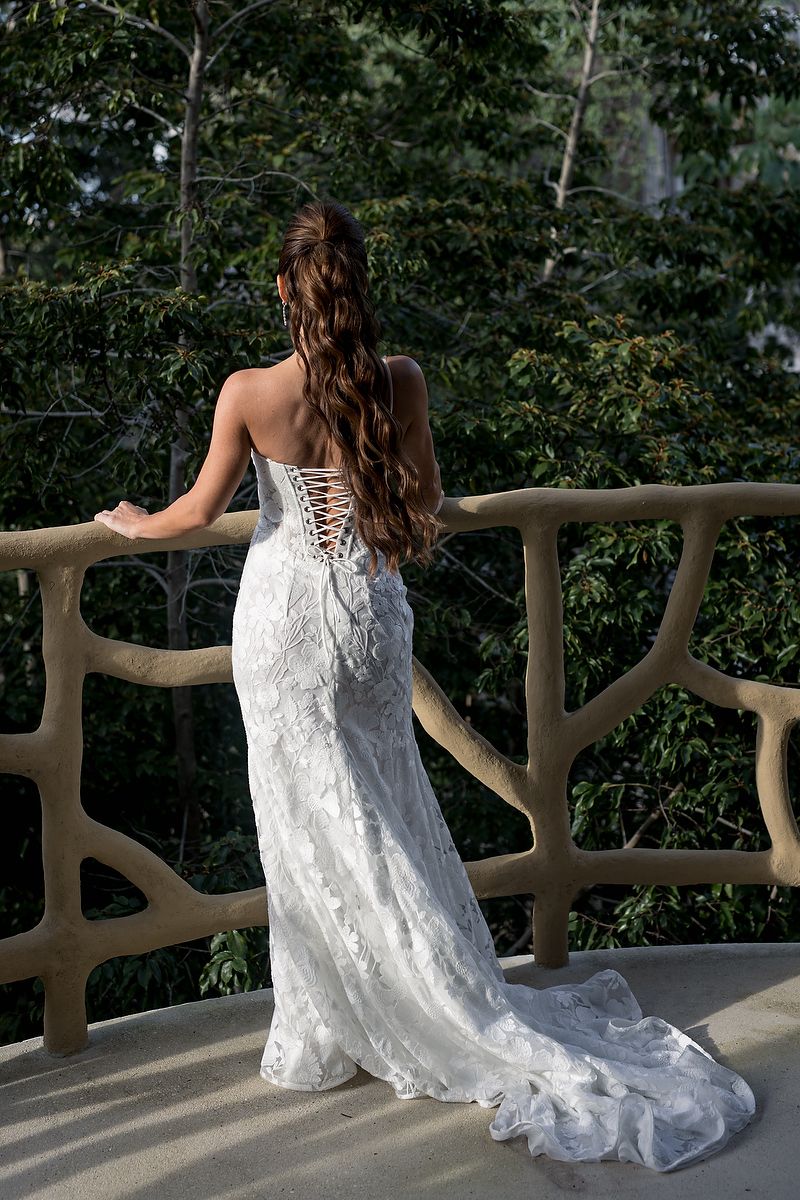 Bride posing on a jungle-view balcony at KAN Tulum, with her lace gown draping along the sculptural architecture.