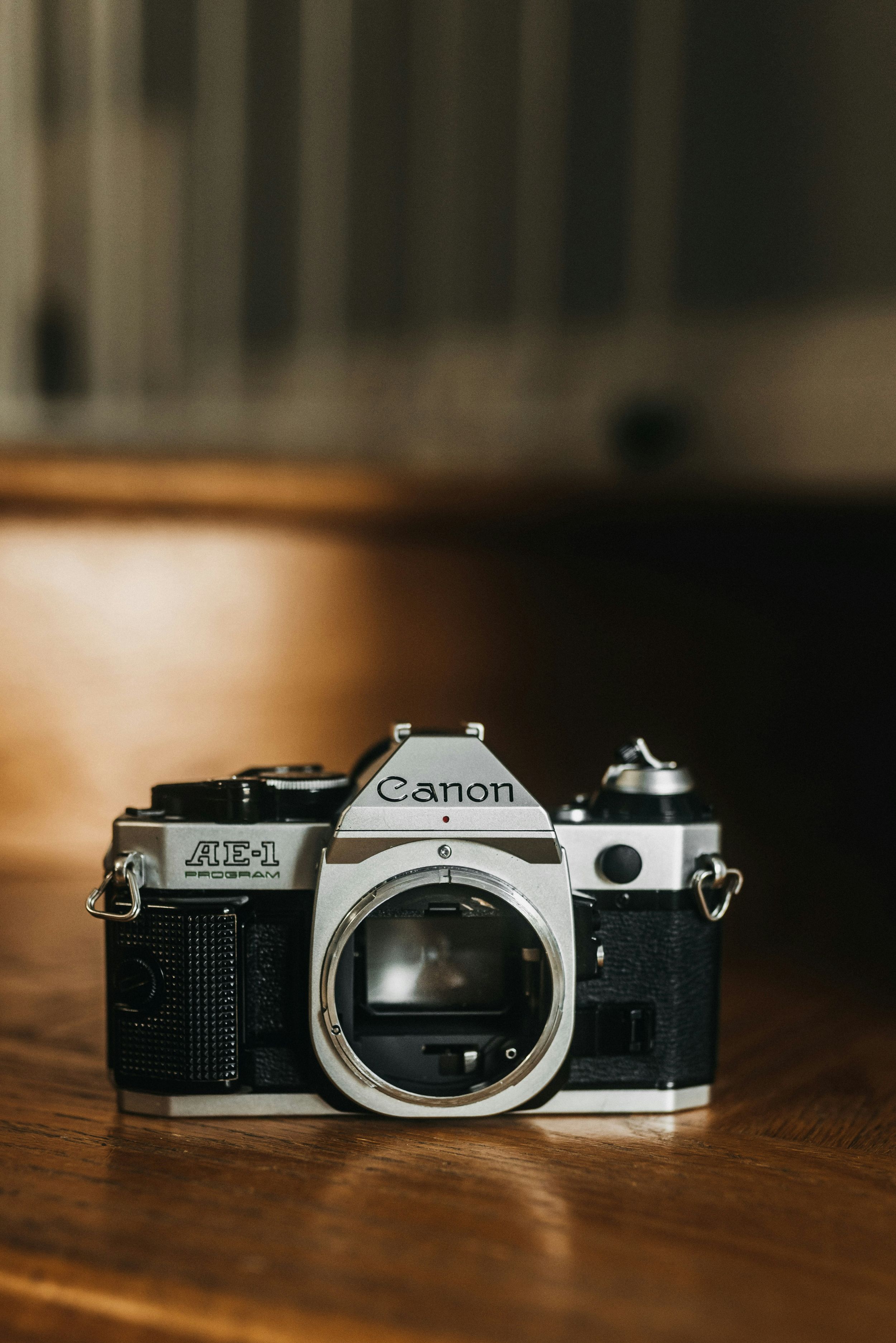 A vintage Canon AE-1 film camera body shown in multiple angles on a wooden surface with dramatic lighting.