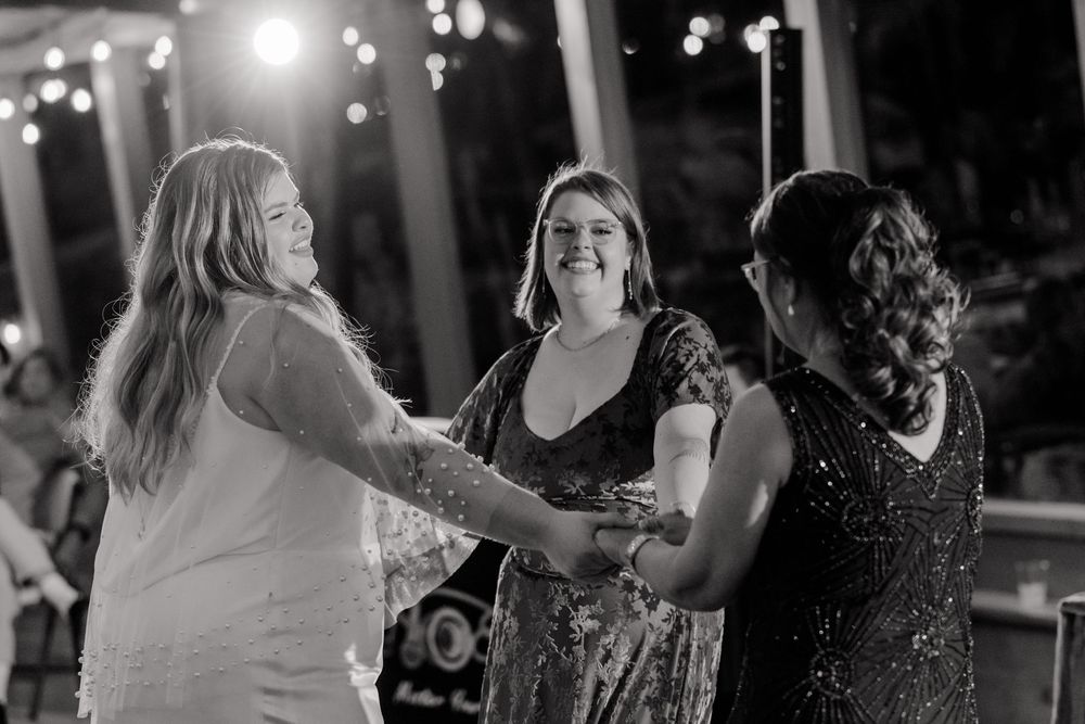 People dancing and celebrating at a nighttime party with glowing lights in the background.