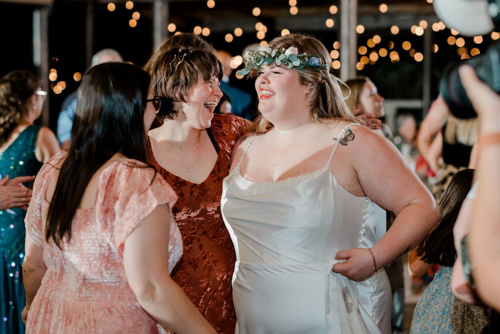 Wedding guests dancing together under string lights at an indoor reception venue.