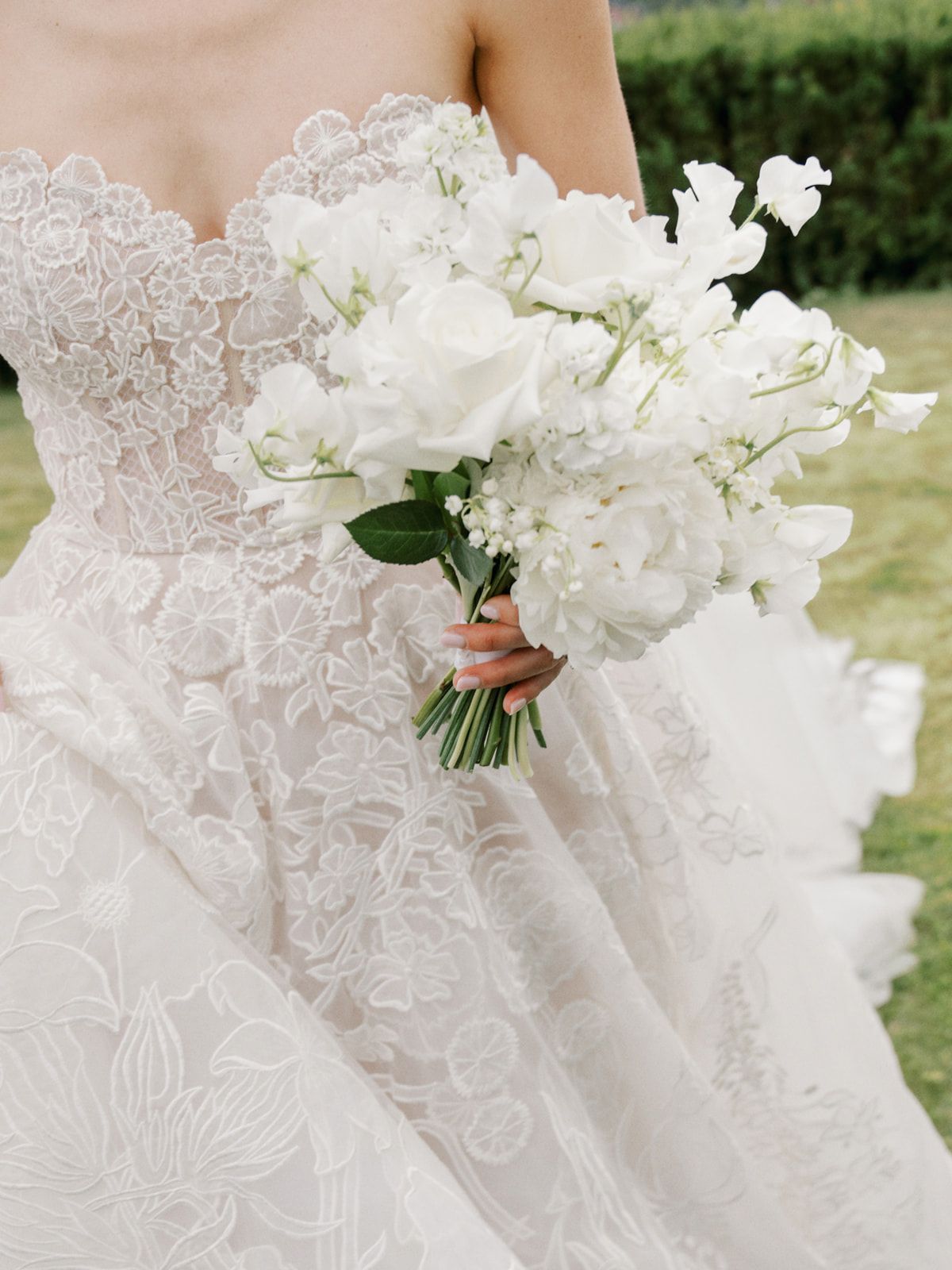 Close-up details of delicate white lace wedding dress fabric and a pristine white floral bouquet.