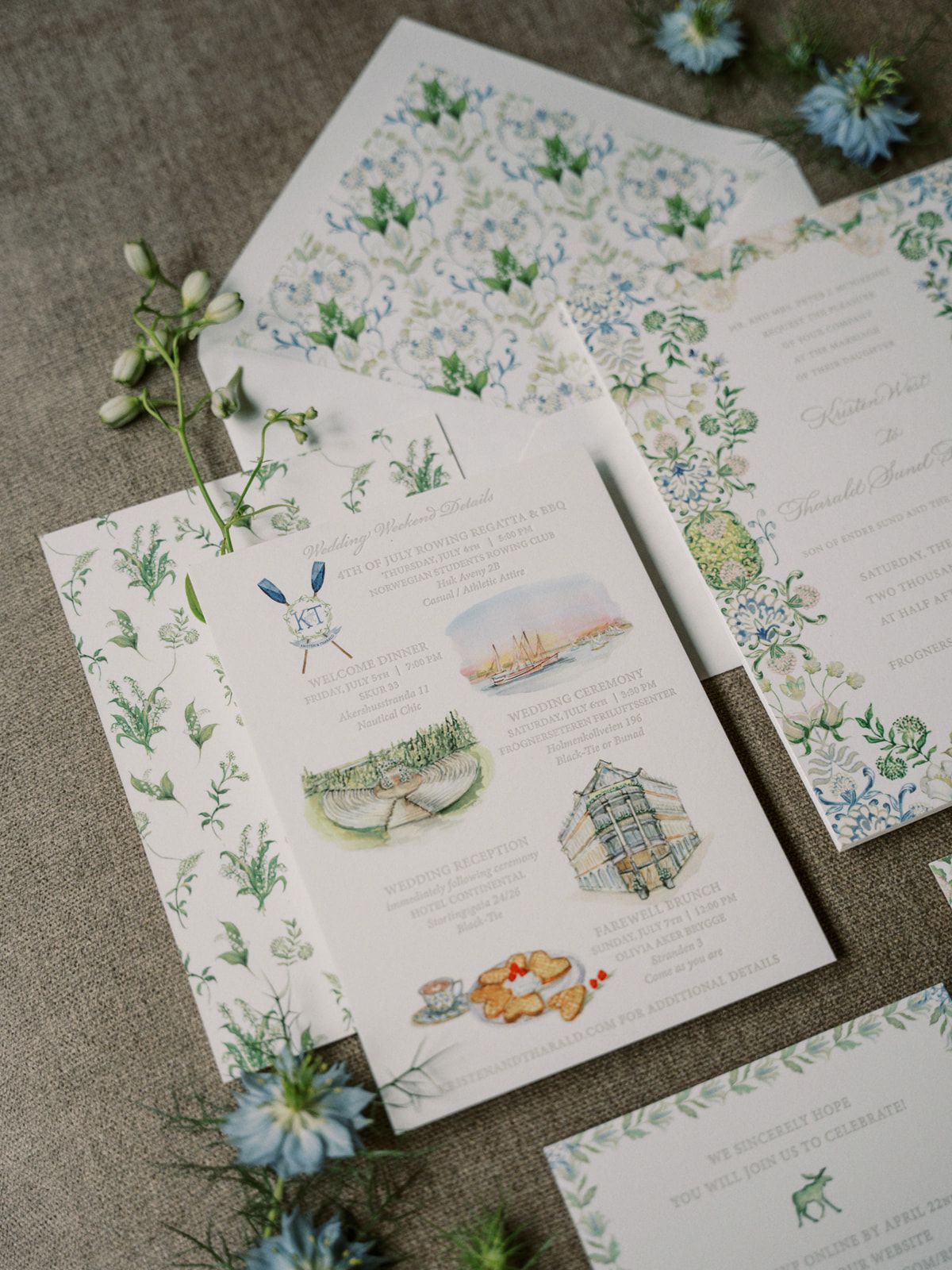 Delicate watercolor wedding stationery with floral designs, illustrations and blue flowers on gray linen background.