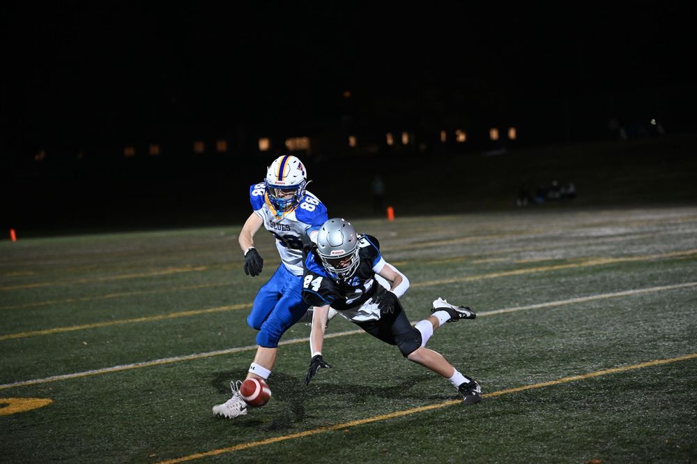 Football players dive and tackle during an intense night game on the field.
