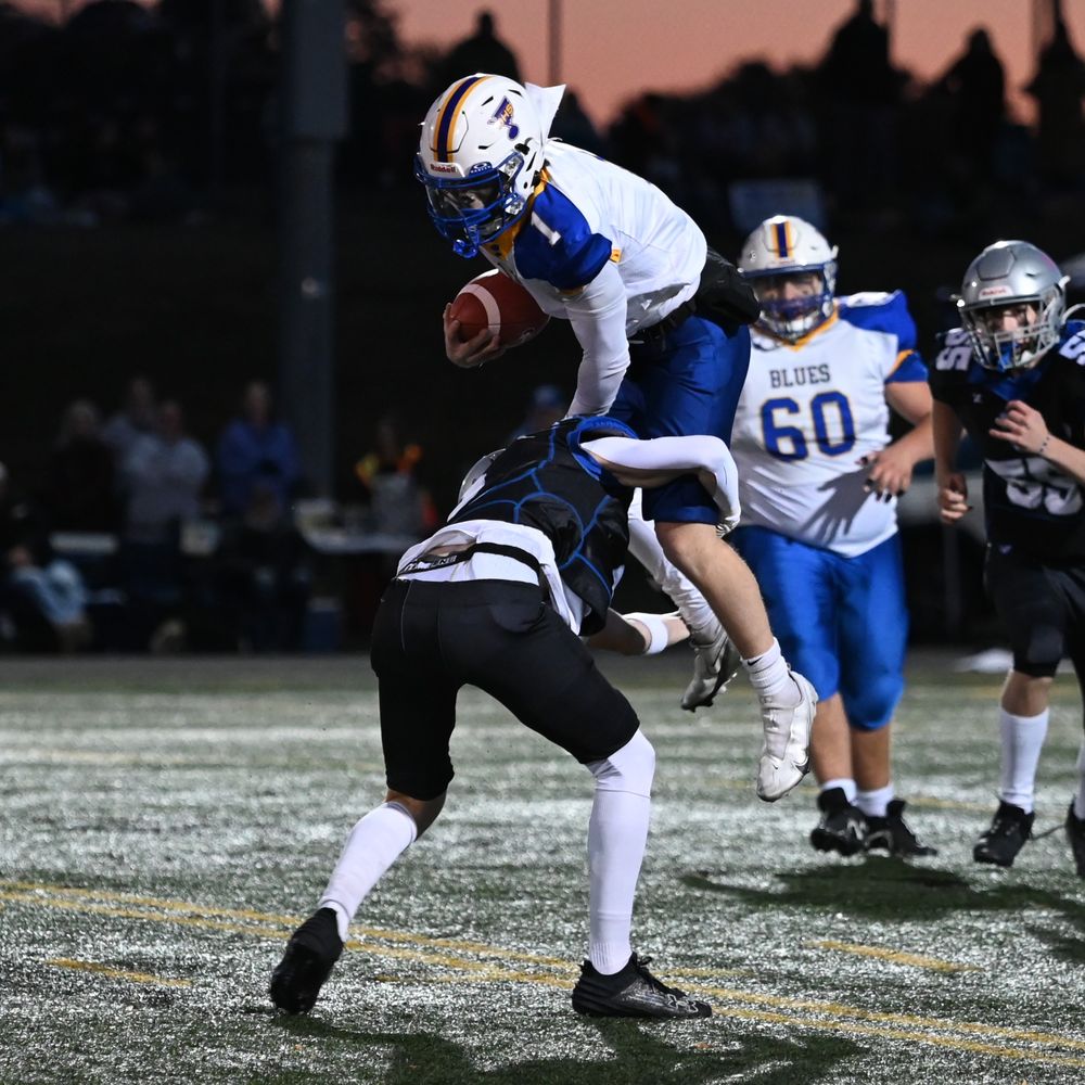 Football players compete for ball control during an intense ground play on the field.