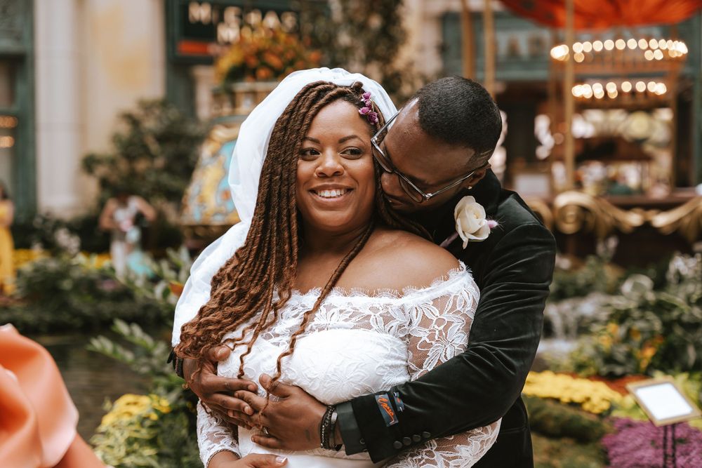 A happy couple shares an intimate moment during their outdoor garden wedding celebration with glowing lights.
