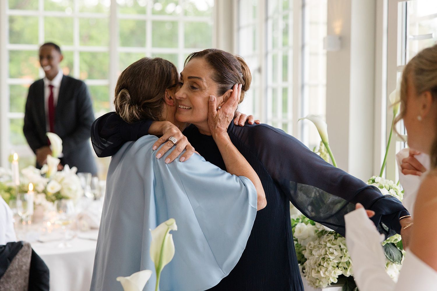 A wedding celebration scene with people dancing and enjoying themselves in an elegant white reception venue.