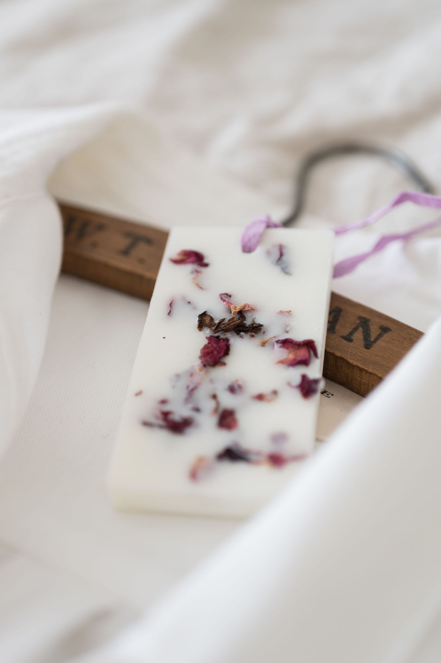 Floral patterned kitchen linens and aprons hanging on wooden wall hooks with gold accents.