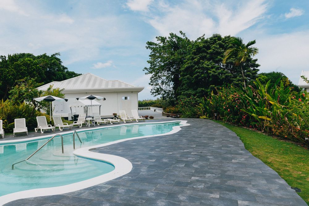 Curved swimming pool with grey stone deck and lush tropical landscaping at a luxury resort property.