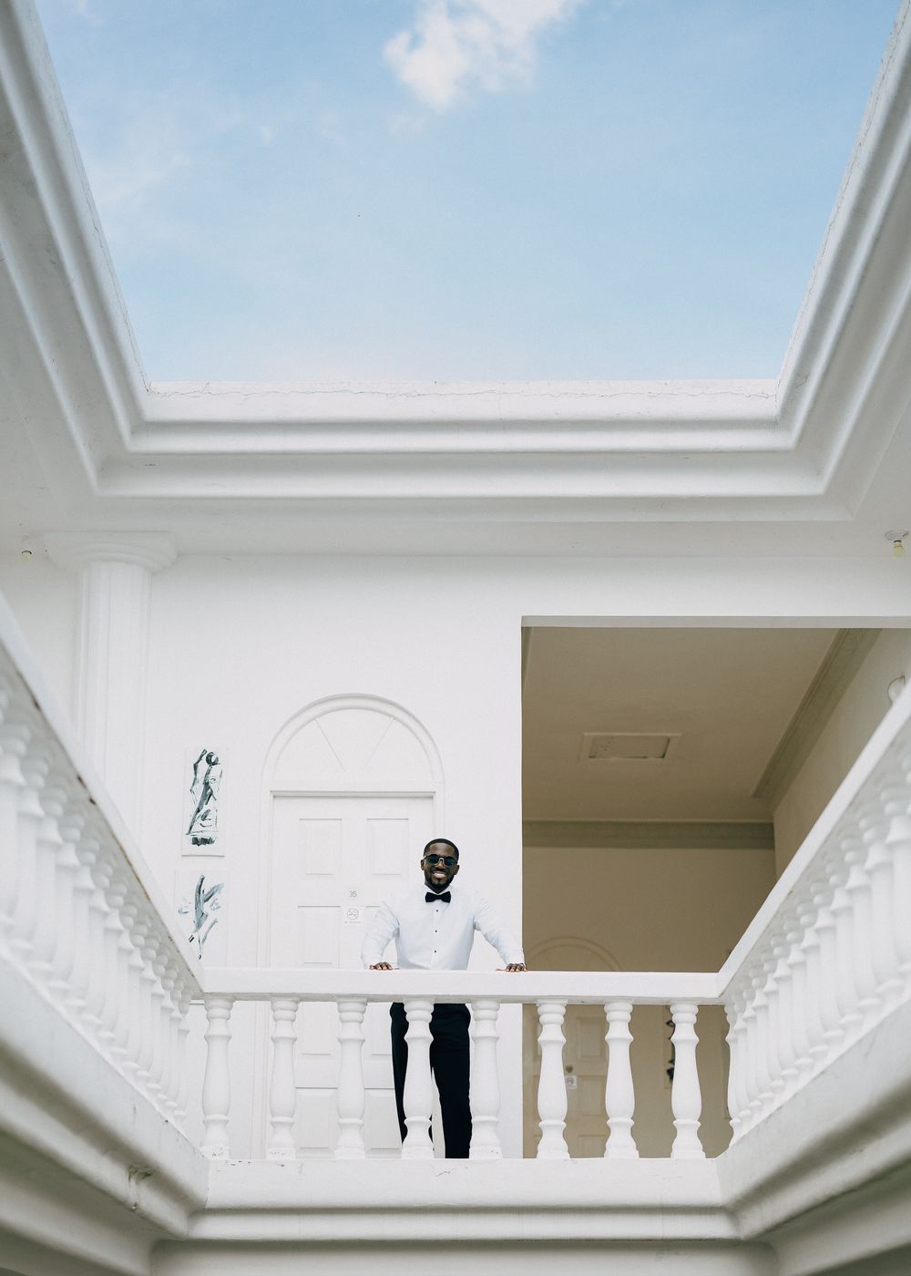 Architectural detail of white ornate crown molding and decorative balustrade columns against a bright skylight ceiling.