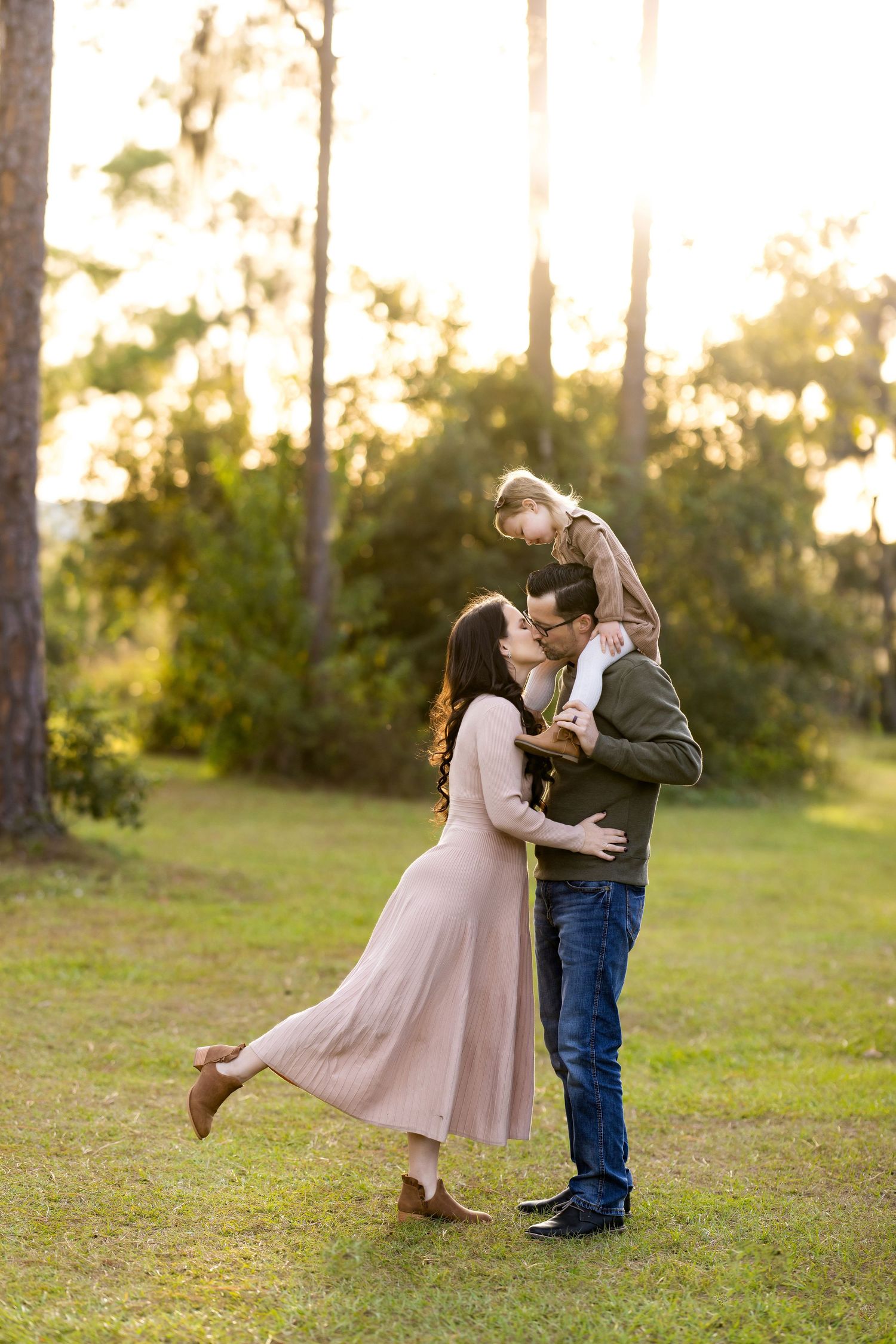 A romantic sequence of dance poses in a grassy field at sunset with soft golden light filtering through trees.