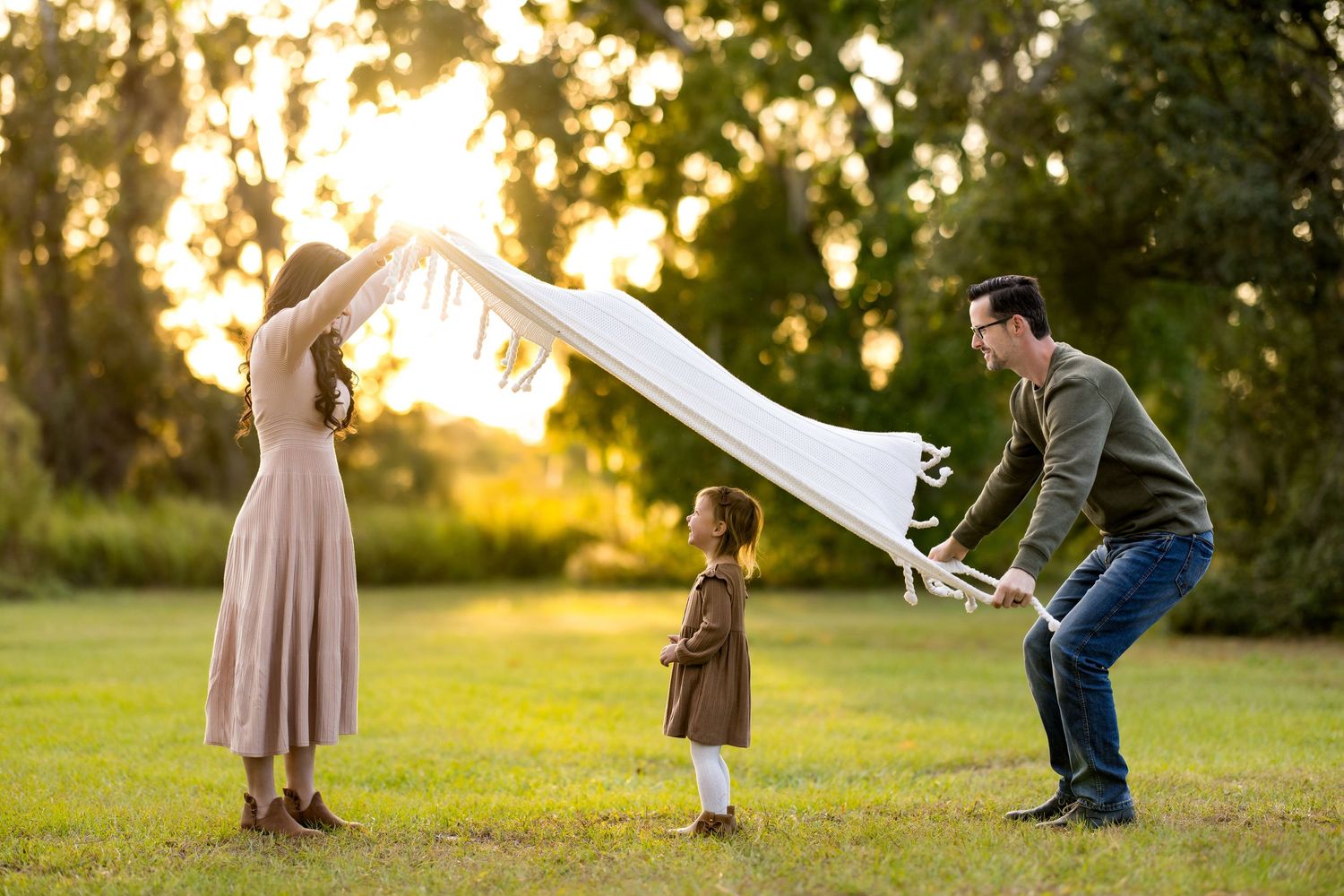 A couple dances together in a grassy field during golden hour sunset creating a romantic silhouette.