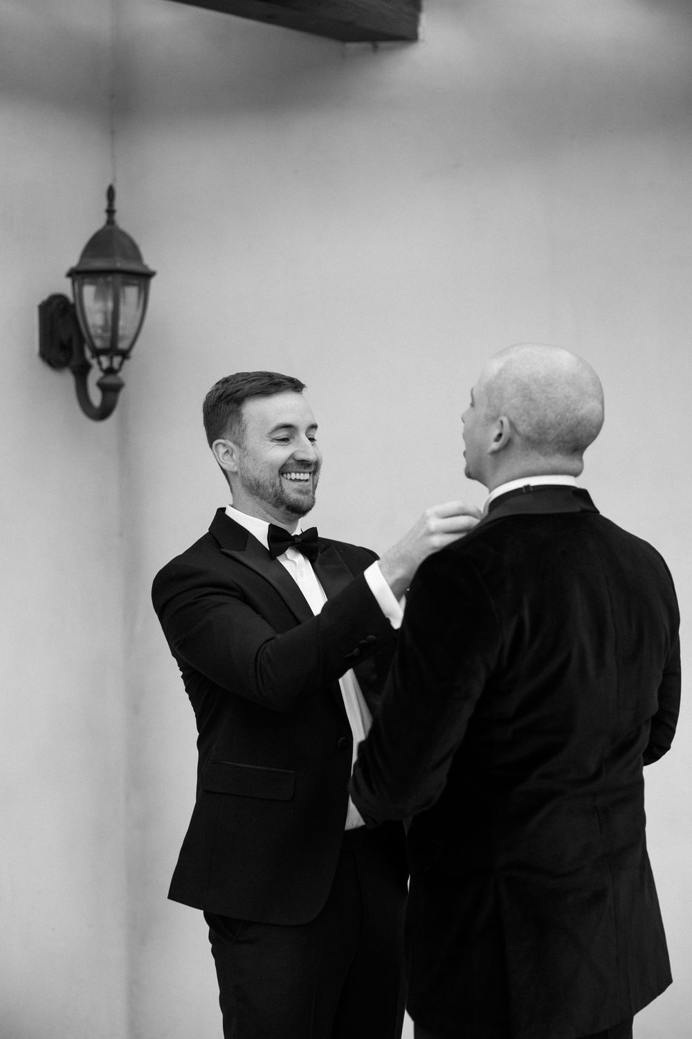 Black and white candid moment between two people in formal attire sharing laughter.