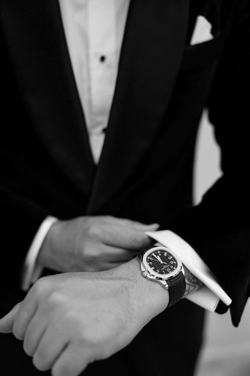 Close-up detail shot of formal watch and tuxedo sleeve.
