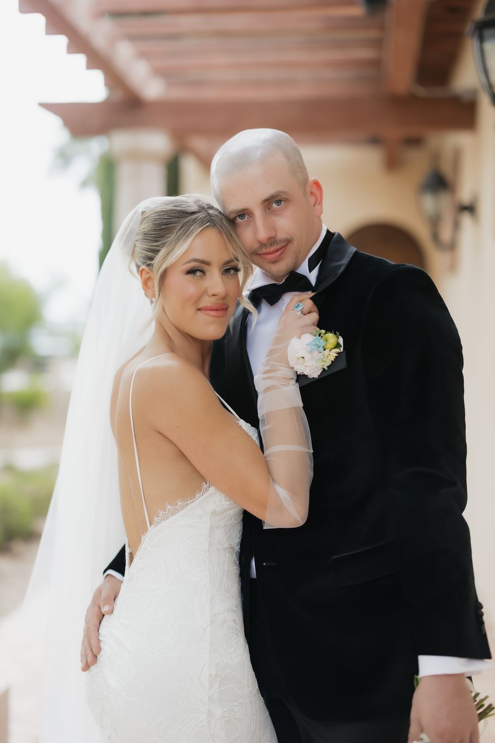 Wedding couple shares intimate moments in formal attire under covered walkway.