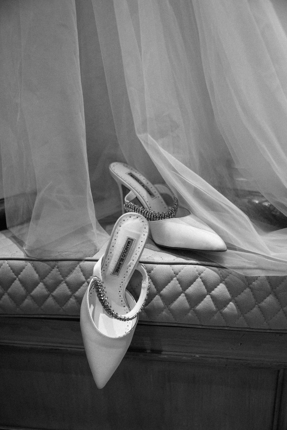 Elegant white bridal shoes arranged artistically on a tufted bench.