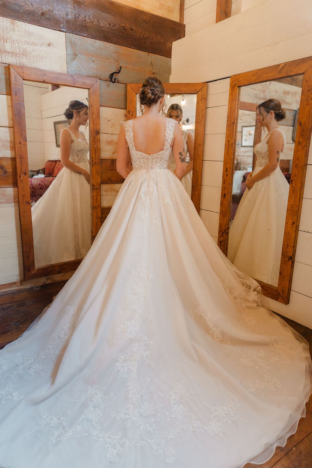 A stunning white wedding dress with a long train and lace details shown from multiple angles in a bridal fitting room.