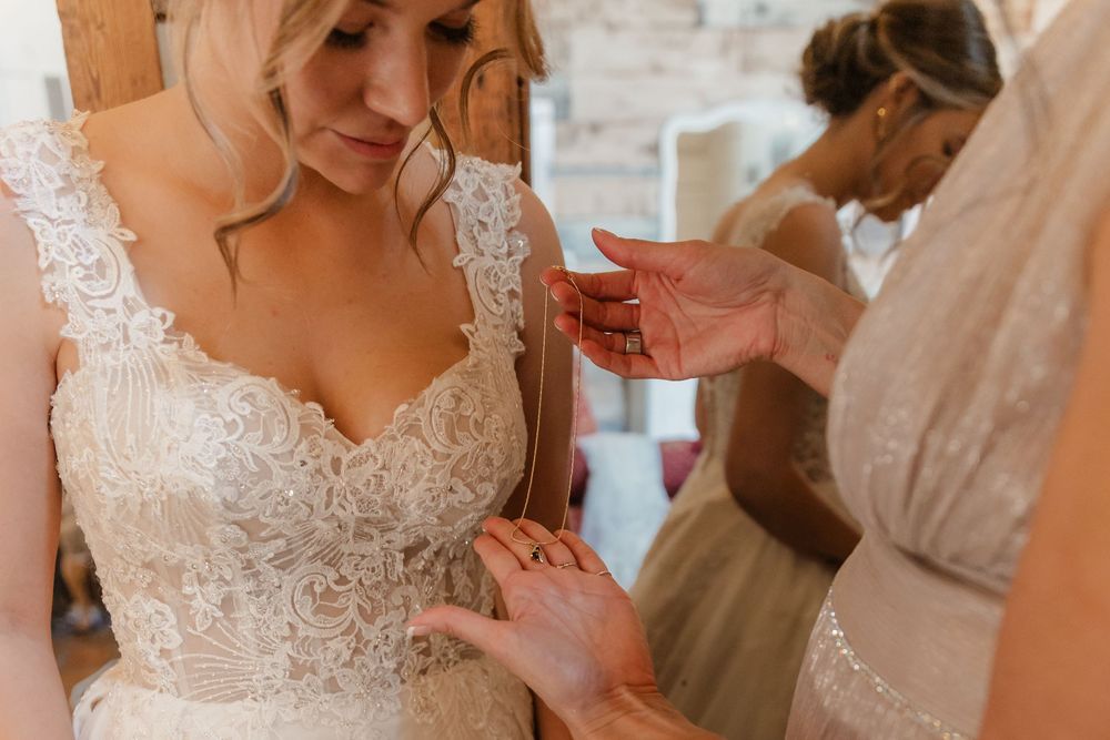A group of people in formal wedding attire gather together while helping with final preparations before a ceremony.