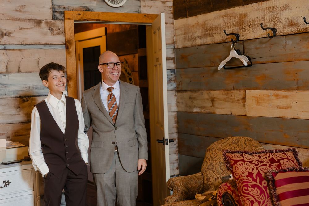People gather in a rustic wooden cabin interior with red decorative pillows and vintage furnishings.