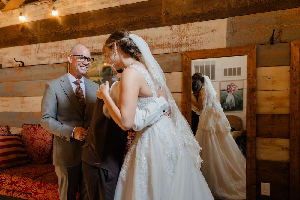Couples dancing together during a rustic barn wedding reception with warm lighting and wooden walls.