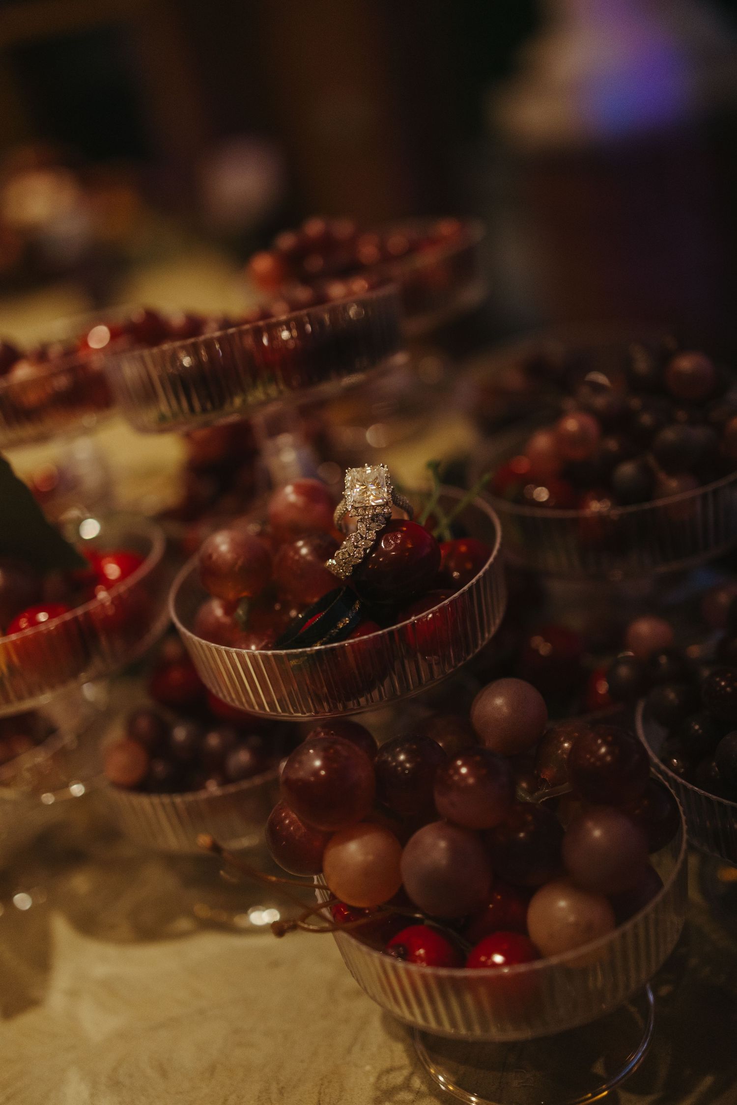Small glass bowls filled with chocolate covered cherries and candies arranged in a row with soft lighting.