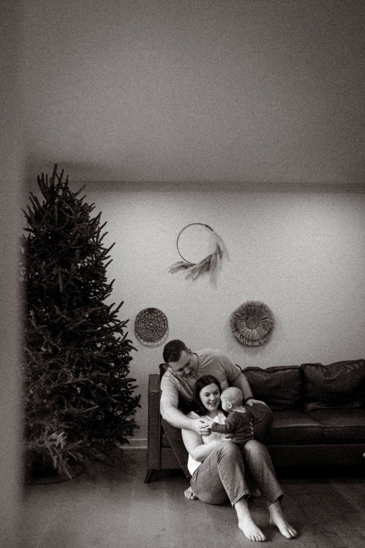 A black and white photo series showing a person in various poses with a Christmas tree and floating paper decorations in Arlington Heights
