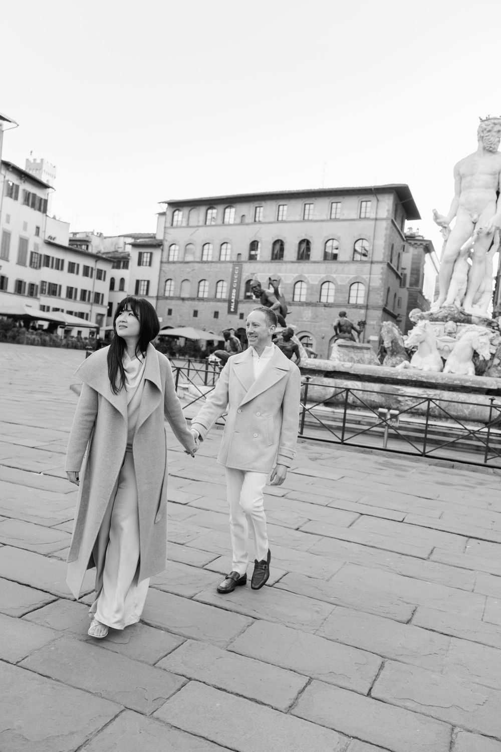A romantic black and white photo series of a couple in light colored outfits sitting by a waterfront Florence Tuscany couples photographer.